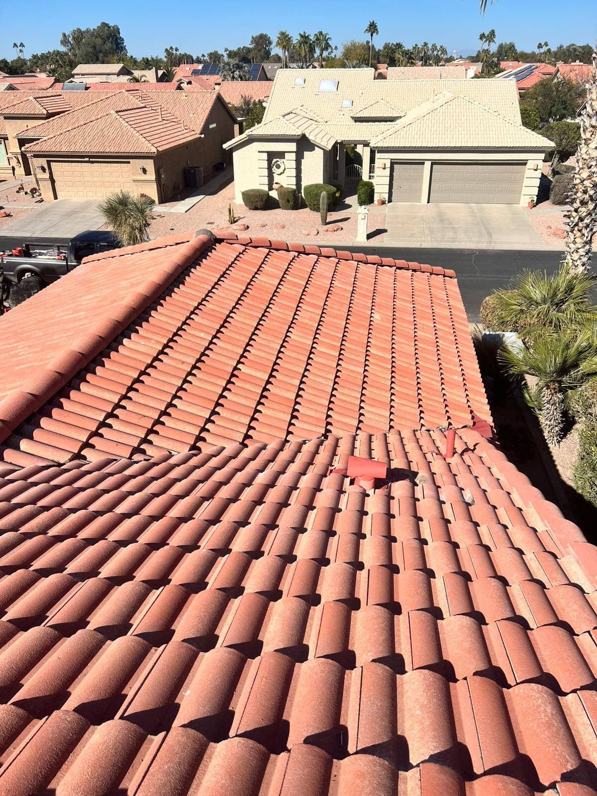 Freshly laid terracotta tile roof seen from the ridge, looking out over a desert neighborhood of tile-roofed homes